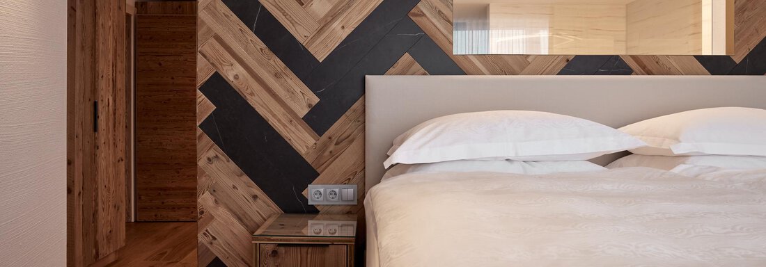 Ein modernes Schlafzimmer mit einem gemütlichen Bett und Holzverkleidung. Die Wände sind mit stilvollen Holzpaneelen in einem gefälligen Muster gestaltet. - TOP Hotel Hochgurgl - Hochgurgl