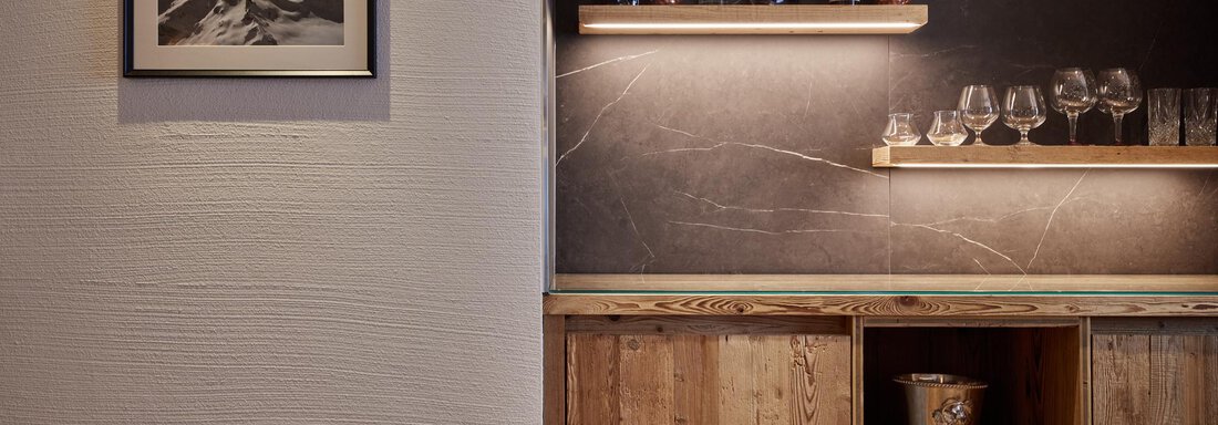 Eine stilvolle Bar mit Holzregalen und Gläsern. An der Wand hängt ein Bild von Bergen. - TOP Hotel Hochgurgl - Hochgurgl