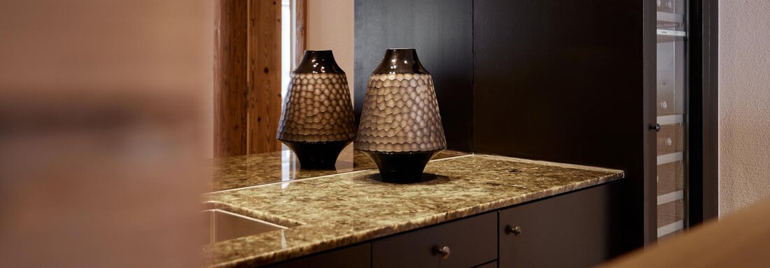 Eine moderne Küche mit einem eleganten Granit-Arbeitsplatz und zwei dekorativen Vasen. Der Raum hat warme Holzakzente und eine stilvolle, schlichte Atmosphäre. - TOP Hotel Hochgurgl - Hochgurgl