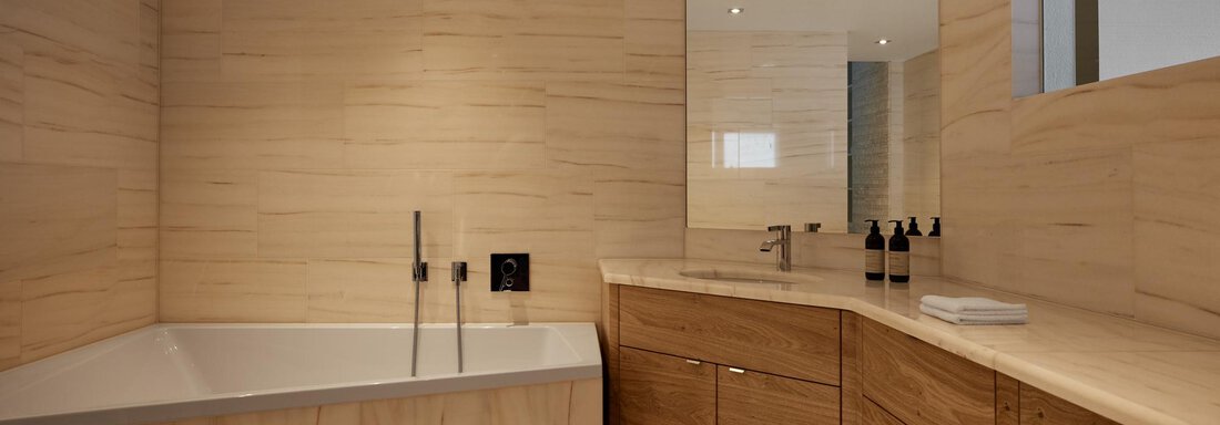 Ein modernes Badezimmer mit einer Badewanne und Holzschränken. Die Wände sind hell und zeitgemäß gestaltet. - TOP Hotel Hochgurgl - Hochgurgl