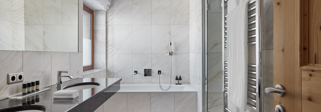 Ein modernes Badezimmer mit eleganter Ausstattung. Es gibt eine Badewanne, eine Dusche und große Spiegel. - TOP Hotel Hochgurgl - Hochgurgl