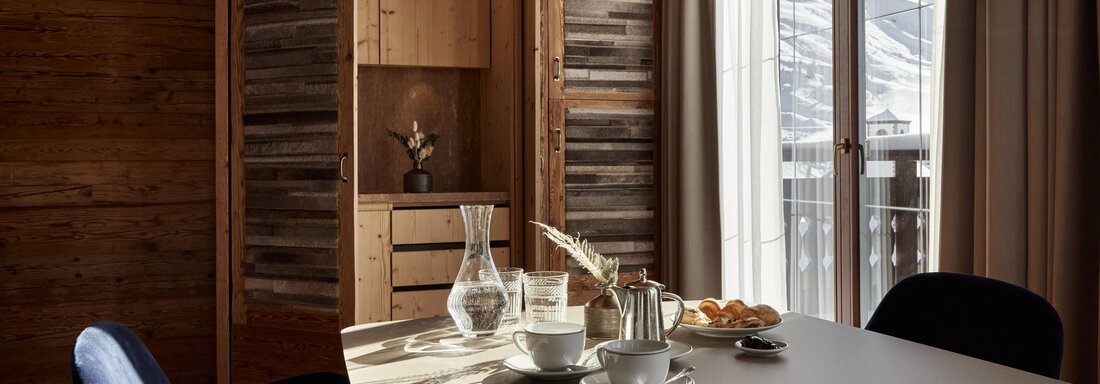 Ein stilvoller Innenraum mit einem großen Tisch und einer Vielzahl von Getränken. Durch die Fenster ist die Berglandschaft im Hintergrund sichtbar. - TOP Hotel Hochgurgl - Hochgurgl