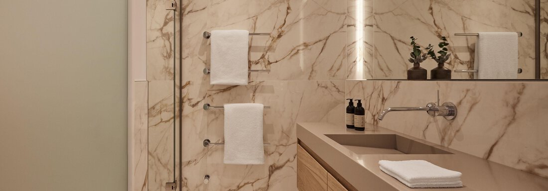 Ein modernes Badezimmer mit eleganten Marmorwänden und Holzdetails. Es ist gut beleuchtet und verfügt über Handtücher sowie Pflegeprodukte. - TOP Hotel Hochgurgl - Hochgurgl