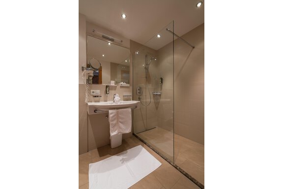 Ein modernes Badezimmer mit einer Glasdusche und einem Waschbecken. Die Wände sind in eleganten neutralen Tönen gehalten. - Hotel Tauferberg - Niederthai