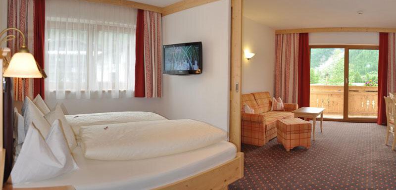 Ein ruhiges Hotelzimmer mit zwei Betten und einem Fernseher. Es gibt einen Balkon mit Blick auf die Landschaft. - Hotel Tauferberg - Niederthai