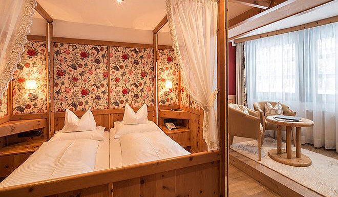 A cozy bedroom with two single beds and floral wallpaper. The room is bright and friendly, with a small seating area and large windows. - Art & Relax Hotel Bergwelt - Obergurgl 