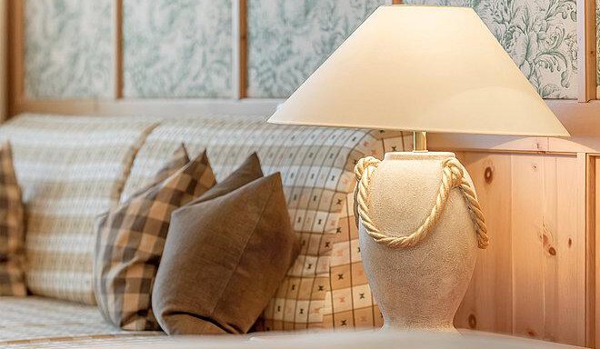 A cozy living room with a sofa and decorative cushions. On a table stands an elegant lamp made of stone. - Art & Relax Hotel Bergwelt - Obergurgl 