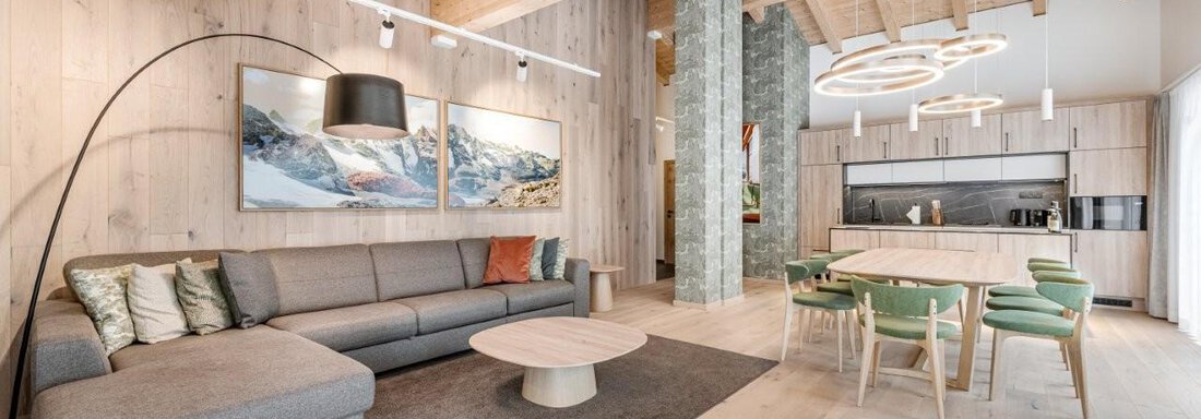 260824_161230-HDR Ein modernes Wohnzimmer mit Holzwänden und einem gemütlichen Sofa. Der Essbereich mit einem runden Tisch und grünen Stühlen ist hell erleuchtet. - Chalet Obergurgl luxury apartments - Obergurgl