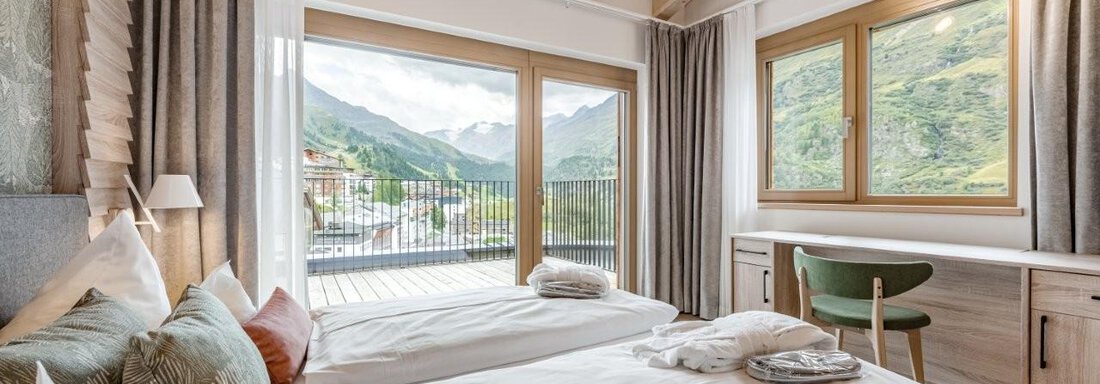 Ein modernes Schlafzimmer mit zwei Betten und Aussicht auf die Berge. Große Fenster sorgen für viel Tageslicht und eine gemütliche Atmosphäre. - Chalet Obergurgl luxury apartments - Obergurgl 