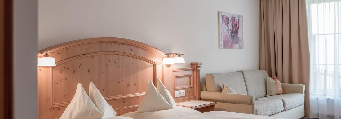 Schlafzimmer A cozy bedroom with a large bed and a sofa. Bright colors and natural wood details create an inviting atmosphere. - Ferienwohnung de Luxe Alpenresidenz am Mühlbach - Obergurgl