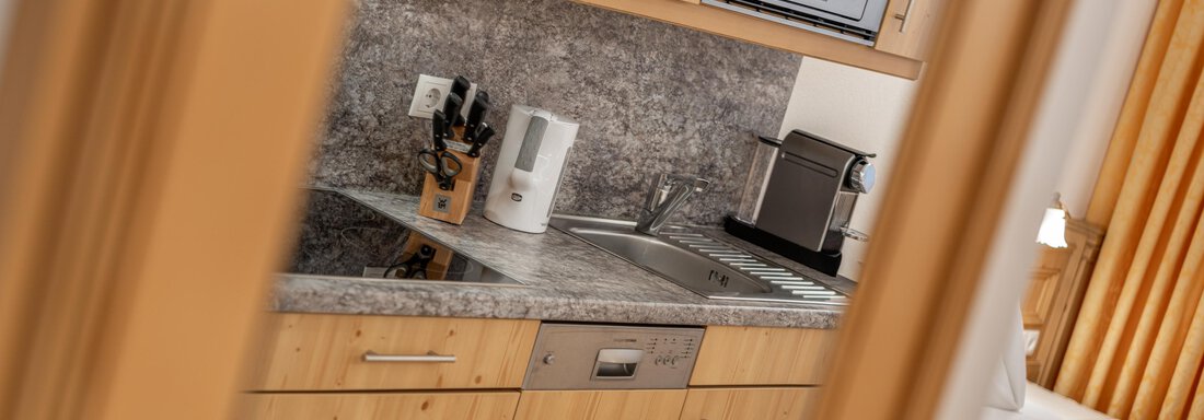 A modern kitchen with wooden cabinets and a granite surface. The equipment includes a microwave, a kettle, and cooking utensils. - Ferienwohnung de Luxe Alpenresidenz am Mühlbach - Obergurgl 