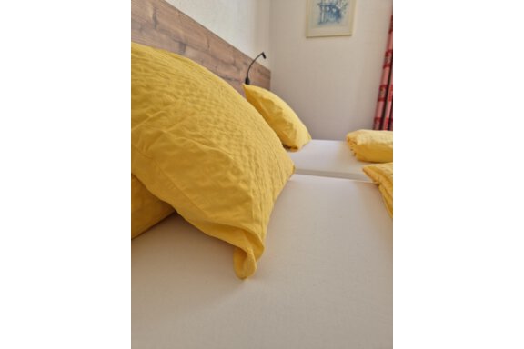 A cozy bedroom with two beds and yellow pillows. The room appears bright and inviting. - Ferienwohnung Fabian - Obergurgl 