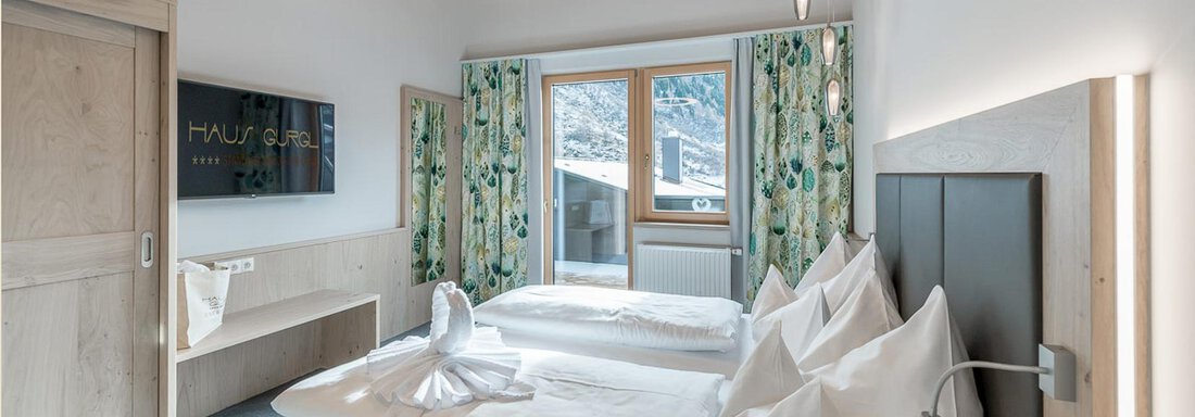 Ein modernes Zimmer mit zwei Betten und eleganter Holzausstattung. Große Fenster bieten Licht und einen Blick nach draußen. - Skihotel Haus Gurgl - Obergurgl 