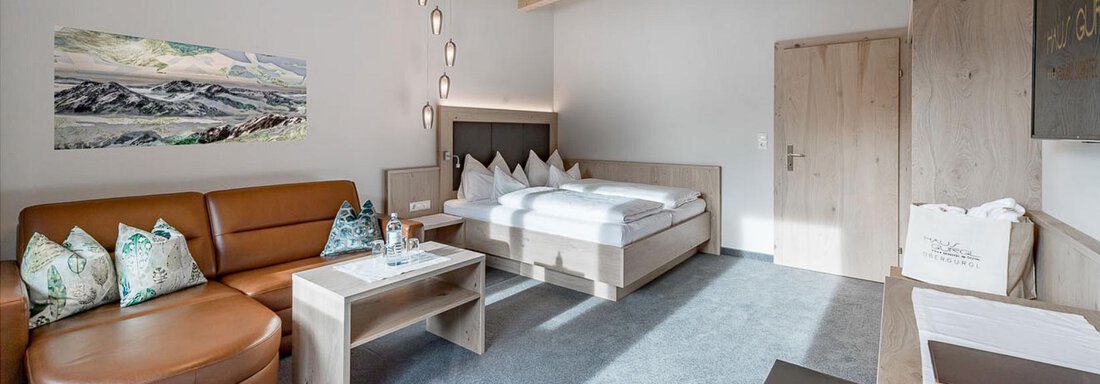 Wohn- Schlafbereich Penthouse Suite „402“ Ein modernes Zimmer mit hellem Holzdekor und einem gemütlichen Sitzbereich. Das Schlafzimmer enthält ein großes Bett und wird von natürlichem Licht durchflutet. - Skihotel Haus Gurgl - Obergurgl