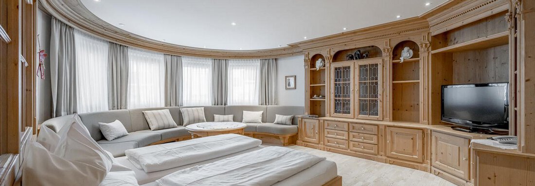 Wohn-Schlafzimmer Ein modernes Zimmer mit Holzvertäfelungen und großen Fenstern. Es gibt zwei Betten, eine Sitzecke und einen Fernseher in einem stilvollen Möbelstück. - Skihotel Haus Gurgl - Obergurgl
