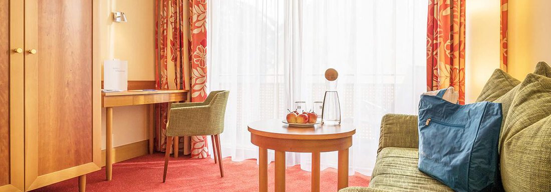 Vivea Hotel Umhausen single room | © Hannes Dabernig (CC BY) A cozy living area with a green sofa and a small table. Large windows provide plenty of daylight and a pleasant space. - Vivea 4* Hotel Umhausen im Ötztal - Umhausen