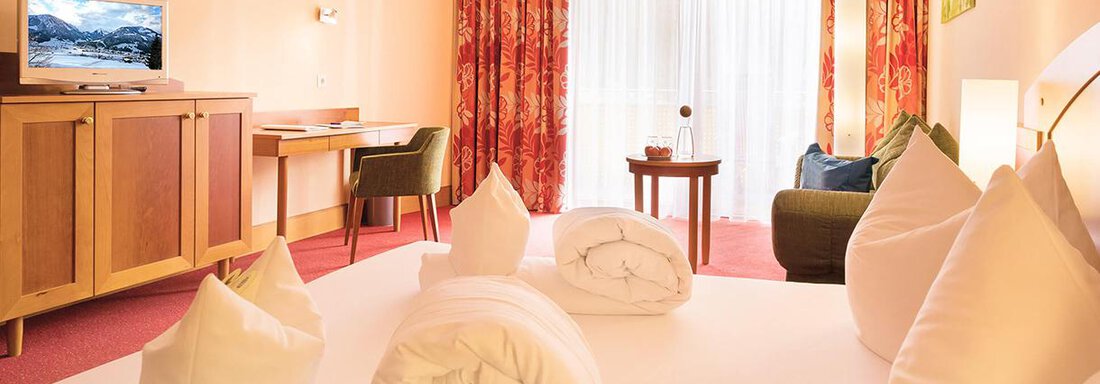 A comfortable hotel room with a large bed and two fresh pillows. The windows let in a lot of light and the room is stylishly furnished. - Vivea 4* Hotel Umhausen im Ötztal - Umhausen