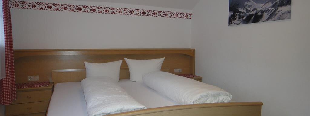 A simple bedroom with two single beds and white pillows. A mountain picture hangs on the wall, and there are light wood details. - Haus Elisabeth - Vent