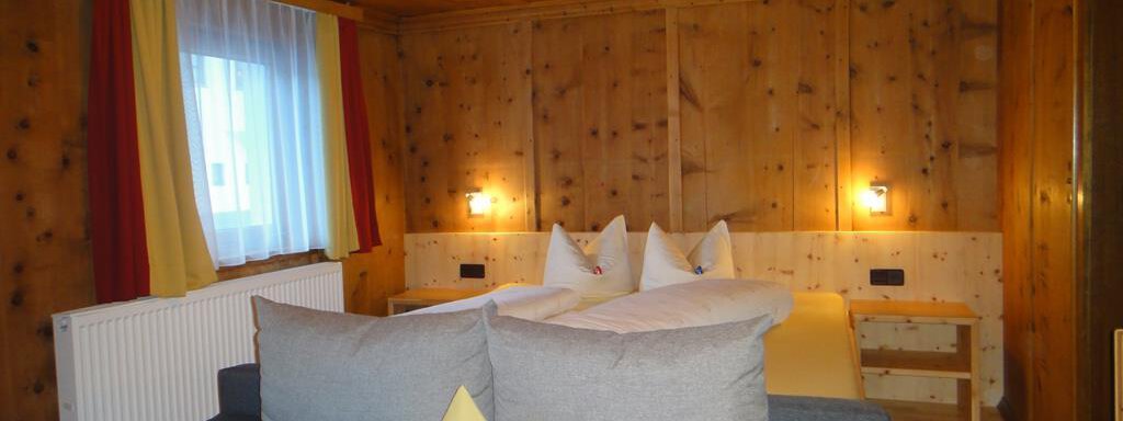 A cozy room with wood paneling, two single beds, and a sofa. Large windows let in plenty of light. - Haus Elisabeth - Vent