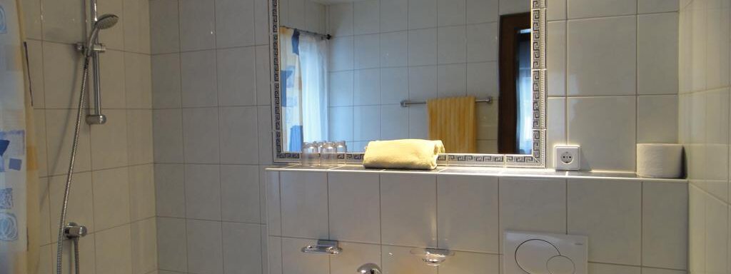 A bright bathroom with white tiles and a bathtub. In the background, towels and a large mirror can be seen. - Haus Elisabeth - Vent