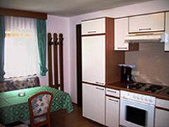 A small, cozy kitchen with a table and chairs. The walls are painted in bright colors, and there are modern kitchen appliances. - Haus Elisabeth - Vent